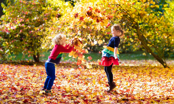 Zwei Kinder spielen im herbstlichen Laub