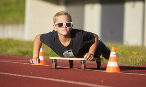 Ein Junge rollt auf einem Rollbrett über den Sportplatz