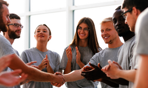 Eine Gruppe von jungen Menschen gibt sich im Kreis die Hand