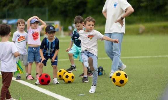 Kinder spielen auf dem Sportplatz Fußball